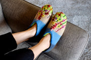 a woman&#39;s feet in colorful slippers on a couch