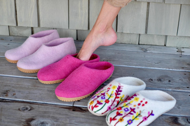 a person standing on a porch next to three pairs of slippers